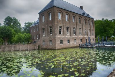 Canal by building against sky