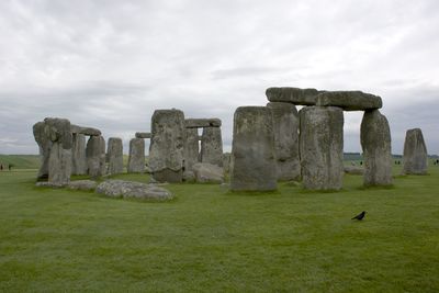 Old ruins on grassy field against cloudy sky