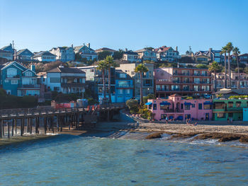 Buildings by river against clear sky