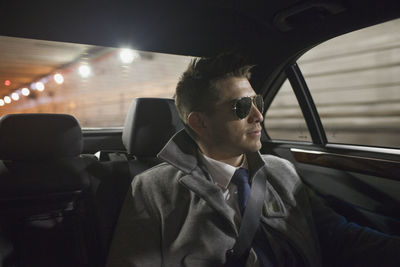 Young businessman looking looking out the window sitting in car service limousine