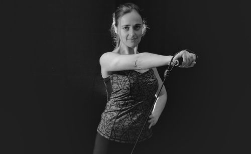 Portrait of woman exercising with resistance band against black background