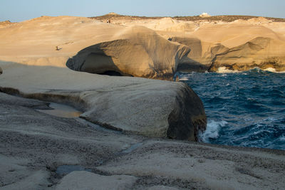 Rock formation on beach against sky