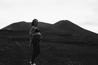 Full length of pregnant woman standing on field against sky