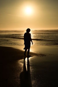 Silhouette woman at beach against sky