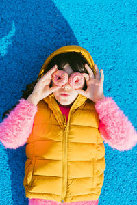 Girl looking through donuts while lying on basketball court