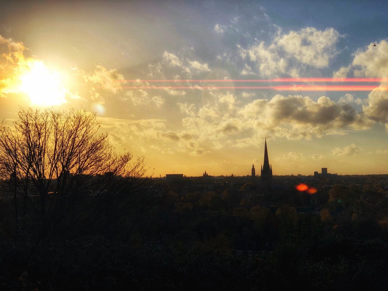 SILHOUETTE OF TREES AND BUILDINGS AGAINST SKY DURING SUNSET