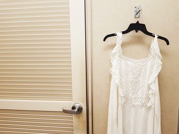 White dress hanging against wall at home