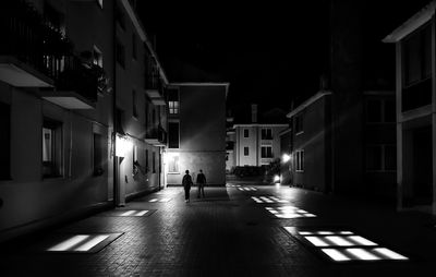 People walking on street amidst buildings at night