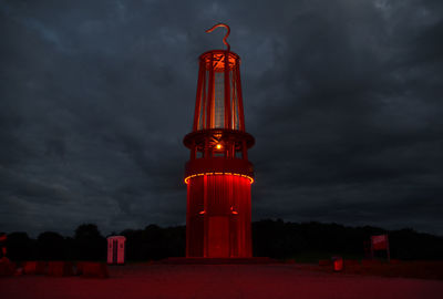 Low angle view of communications tower against cloudy sky