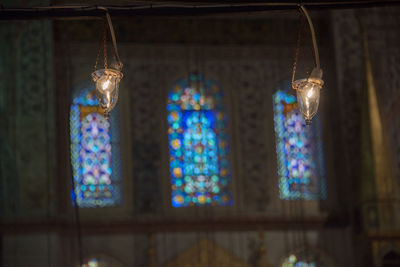 Low angle view of old-fashioned lighting equipment hanging against building