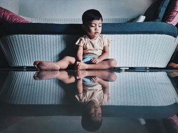 Full length of cute boy sitting on sofa