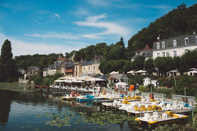 Boats moored at harbor by buildings in city against sky