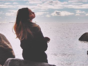 Side view of woman looking at sea against sky