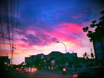 Street by buildings against sky at sunset