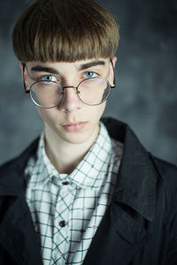 Portrait of young man wearing eyeglasses against wall