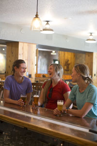 Three female friends enjoy a beer at a brewery in government camp, or.