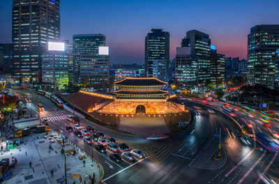 High angle view of illuminated street amidst buildings in city at night