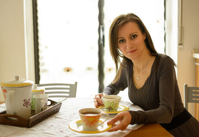 Portrait of smiling woman giving tea at home
