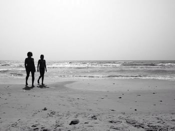 People standing on beach against clear sky