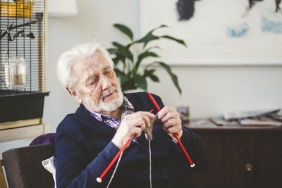 Senior man knitting while sitting in nursing home