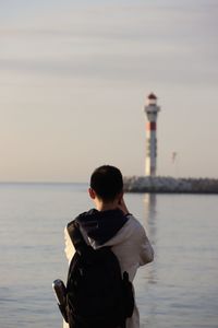 Rear view of man looking at sea against sky