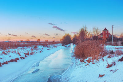 Snow covered land against sky during sunset