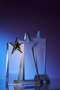 Group of star shape crystal trophies against blue and pink background