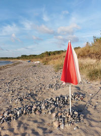 Folded red and white parasol on the emty morning beach of the baltic sea on rügen