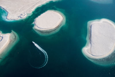 Aerial view of boat sailing in sea by islands