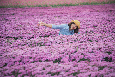 Portrait of woman with pink flowers on field