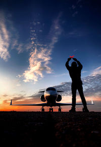 Silhouette man parking a private jet during sunset