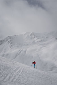 Man skiing on snowcapped mountain against sky