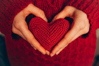 Female hand holding red knitted heart. organ donation, family insurance. 