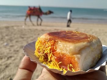 Midsection of person holding ice cream on beach