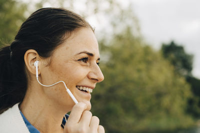 Close-up of smiling woman talking through headphones while looking away