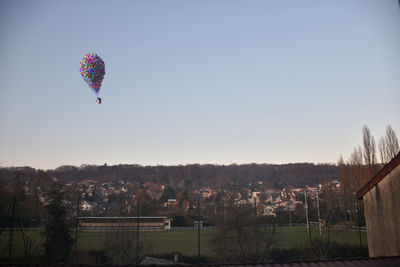 Hot air balloon flying over trees against clear sky