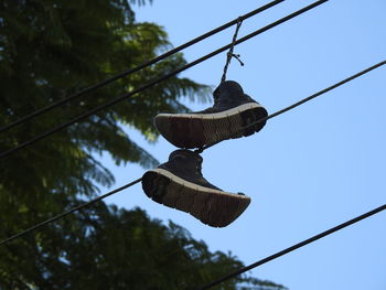 Low angle view of shoes hanging against clear sky