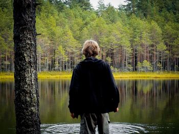 Rear view of man standing on tree trunk