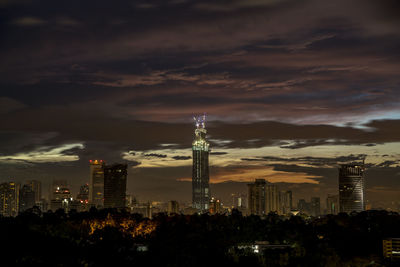 Illuminated buildings in city against sky at night