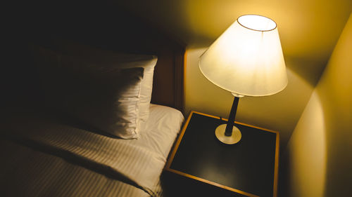 Close-up of electric lamp on bed against wall