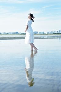 Full length of woman standing in sea against sky