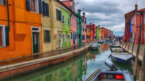 Boats moored in canal amidst buildings in city