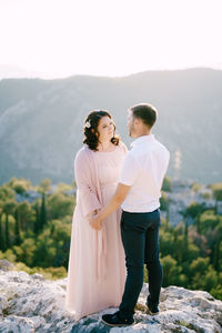 Couple standing on mountain against sky