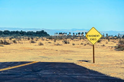 Road signs on landscape against clear blue sky