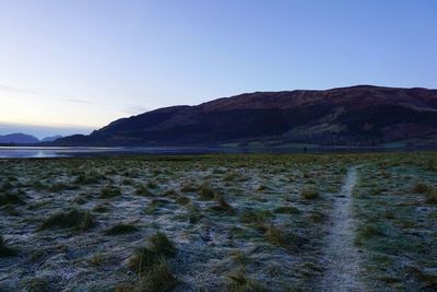 Scenic view of land and mountains against clear blue sky