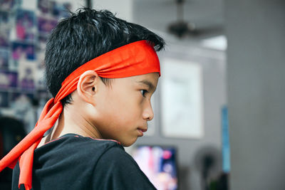 Close-up of boy wearing bandanna while looking away at home