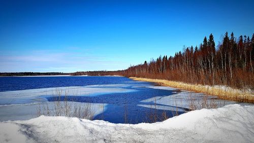 Scenic view of frozen lake against clear blue sky