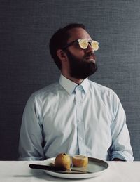 Man wearing eyewear with lemon slices against wall