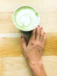 High angle view of hand holding drink on table