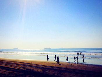 People on beach against clear sky